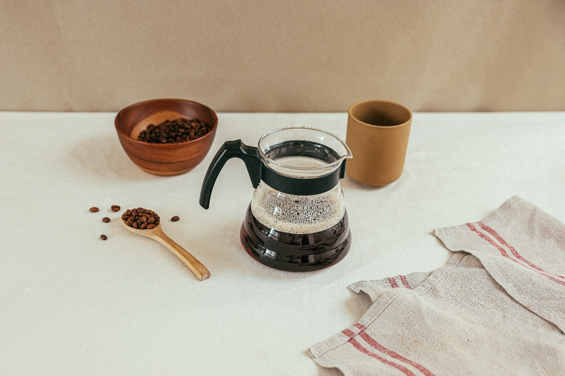 A bowl of coffee beans next to a pitcher